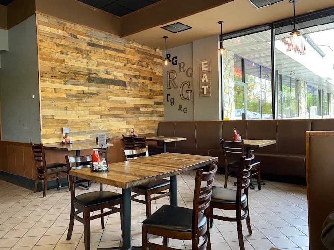 Interior of a casual dining restaurant with wood tables, brown upholstered booths, and a reclaimed wood accent wall